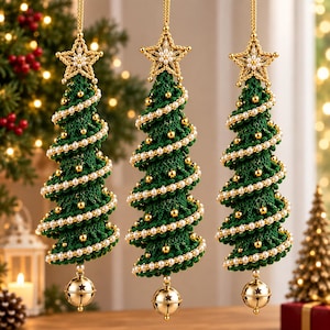 Könnte beinhalten: Drei hängende Weihnachtsbaumschmuckstücke aus dunkelgrünem Garn. Jeder Baum ist mit einer Spirale aus weißen Perlen und kleinen goldenen Perlen verziert, mit einem goldenen Stern gekrönt und mit einer goldenen Glocke an der Basis versehen.