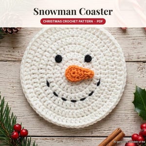 Peut inclure: Un dessous de verre au crochet blanc et rond représentant un bonhomme de neige avec deux yeux noirs, un petit nez orange en forme de carotte et une bouche noire cousue. Le texte "Snowman Coaster" et "CHRISTMAS CROCHET PATTERN · PDF" est visible.