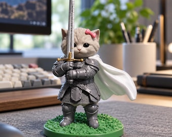 May include: A figurine of a fluffy gray cat wearing silver plate armor and a white cape, holding a long sword with both paws. The cat has a small pink bow on its head and stands on a green circular base with the name Emily printed on it.