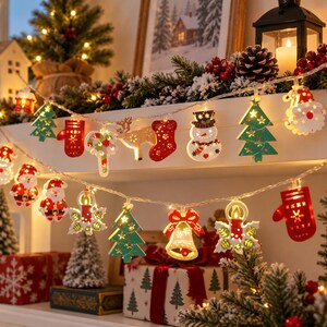 Op de afbeelding: Een snoer met LED-kerstverlichting voorzien van diverse houten uitsparingen waaronder de Kerstman, sneeuwpoppen, rendieren, kerstbomen, sokken, wanten, klokken en kaarsen, verlicht met warm wit licht tegen een feestelijke achtergrond.