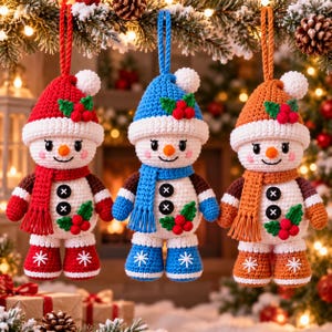 May include: Three crocheted snowman ornaments hanging by braided cords. Each snowman wears a matching hat and scarf, featuring white pom-poms, two black button details, green holly leaves with red berries, and white snowflake patterns on boots.