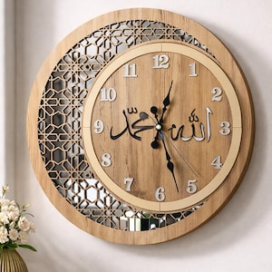 May include: A circular wall clock with a light wood grain finish featuring a crescent moon shape. The clock face displays Arabic calligraphy in black, surrounded by silver-colored numerals from 1 to 12. A geometric lattice pattern fills the crescent.