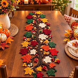 Puede incluir: Un camino de mesa decorativo y alargado con un diseño central de enredadera trenzada marrón, adornado con hojas de arce de ganchillo en tonos rojo, naranja, amarillo, verde y blanco, intercaladas con pequeños racimos de bayas rojas, amarillas y blancas.
