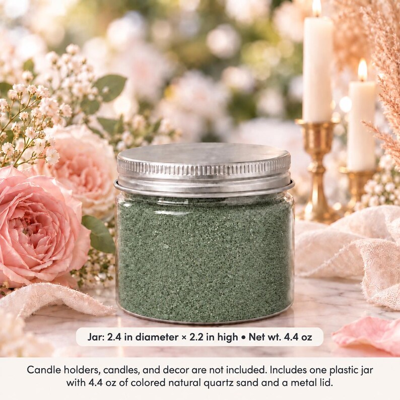 Closed clear jar of Olive Grove colored quartz sand in a soft sage green, with a silver metal screw lid on a marble table, surrounded by pink roses, baby's breath, lit white candles in brass holders and cream fabric. Text: Jar: 2.4 in diameter x 2.2 in high, Net wt. 4.4 oz. Candle holders, candles, and decor are not included. Includes one plastic jar with 4.4 oz of colored natural quartz sand and a metal lid.