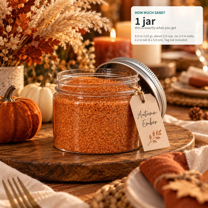Open jar of Autumn Ember orange craft sand with a name tag on a fall table with pumpkins, candles, and dried flowers