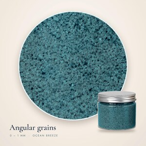 Close-up of Ocean Breeze craft sand showing angular teal grains 0 to 1 mm, with a small closed jar in the corner