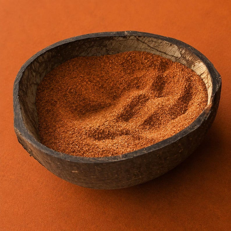 Coconut shell bowl filled with Terracotta Clay colored quartz sand in a warm reddish brown, with soft ripples in the surface, on a matching terracotta orange background.