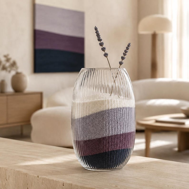 Ribbed glass vase with wavy layers of white, lavender gray, plum, and navy sand and two dried lavender sprigs