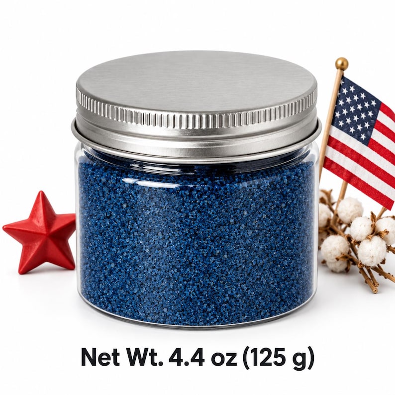 Closed clear jar of royal blue colored quartz sand with a silver metal screw lid, next to a red star, a small American flag and cotton stems, with text: Net Wt. 4.4 oz (125 g).
