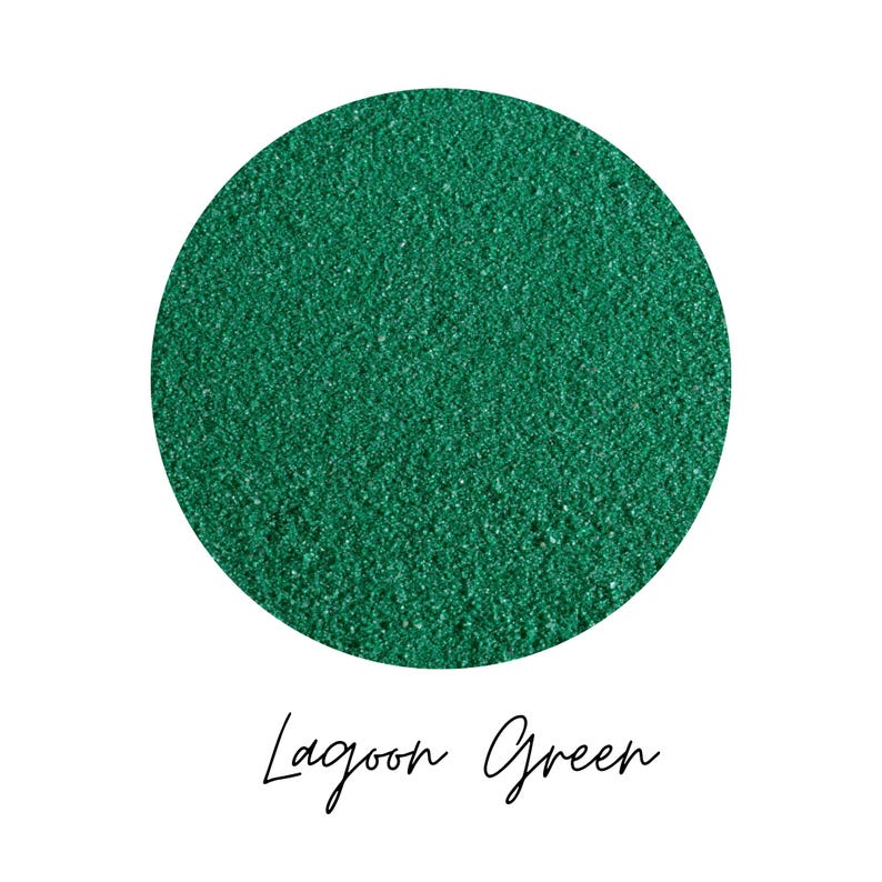 Close-up circle swatch of Lagoon Green emerald craft sand with the color name written below