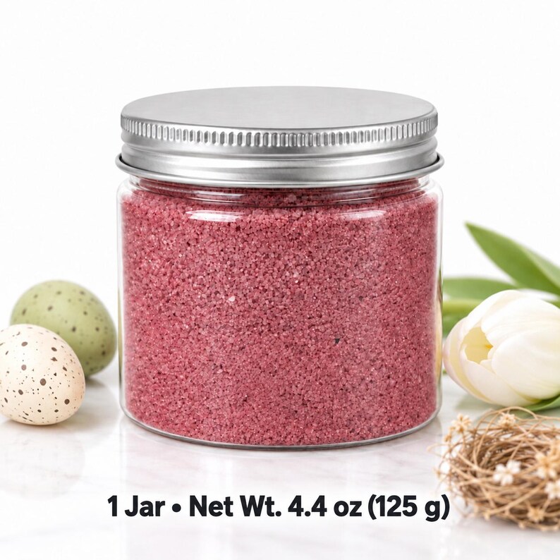 Closed clear jar of Raspberry Bloom colored quartz sand in a soft raspberry pink, with a silver metal screw lid, next to speckled Easter eggs in cream and sage green, a white tulip and a small twig nest, with text: 1 Jar, Net Wt. 4.4 oz (125 g).