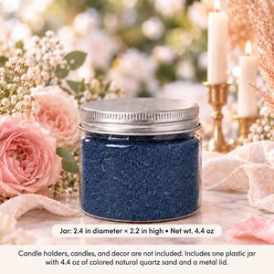 Closed clear jar of royal blue colored quartz sand with a silver metal screw lid on a marble table, surrounded by pink roses, baby's breath, lit white candles in brass holders and cream fabric. Text: Jar: 2.4 in diameter x 2.2 in high, Net wt. 4.4 oz. Candle holders, candles, and decor are not included. Includes one plastic jar with 4.4 oz of colored natural quartz sand and a metal lid.