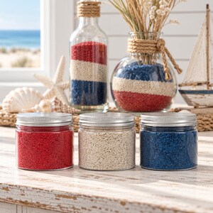Photo 5 – Coastal shelf	Three jars of red, white, and blue craft sand in front of a bottle and vase with striped sand layers and a toy sailboat