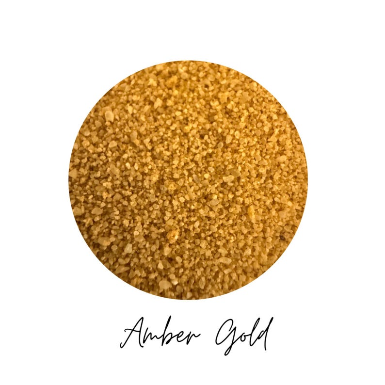 Close-up circle swatch of Amber Gold craft sand with the color name written below