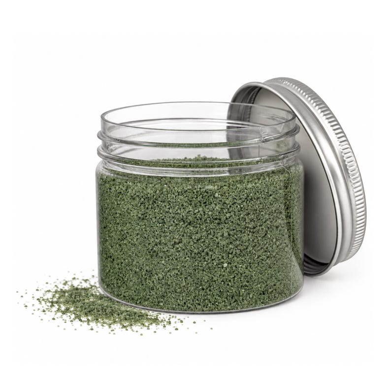 Open jar of Forest Moss green craft sand with its silver lid leaning on the side and a little sand spilled in front
