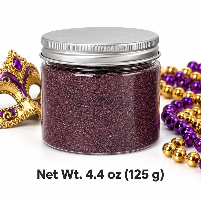 Closed clear jar of Plum Velvet colored quartz sand in a deep plum purple, with a silver metal screw lid, next to a gold and purple masquerade mask and strands of purple and gold beads, with text: Net Wt. 4.4 oz (125 g).