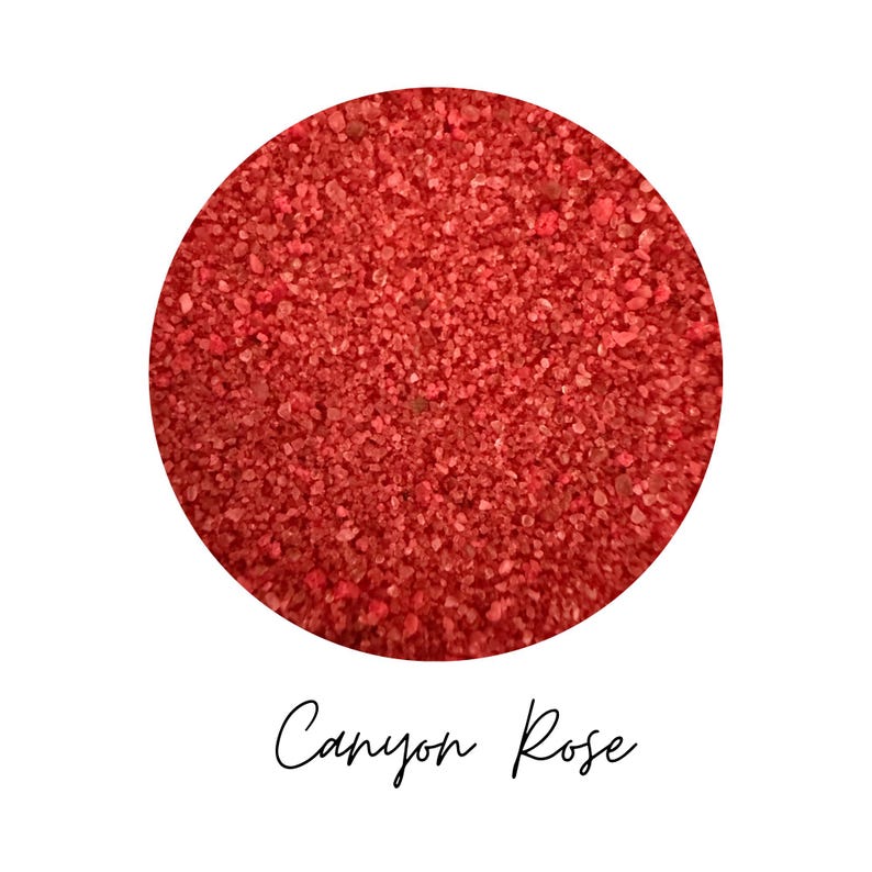 Close-up swatch of Canyon Rose colored quartz sand showing the red-coral shade and natural granular texture