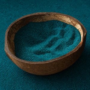 Wooden bowl filled with Caribbean Reef teal colored quartz sand on a matching teal surface