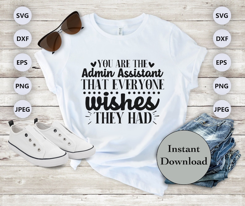 May include: White t-shirt with black text that reads "You are the Admin Assistant that everyone wishes they had". The shirt is laying on a wooden surface with a pair of sunglasses, white sneakers, and a stack of blue jeans.