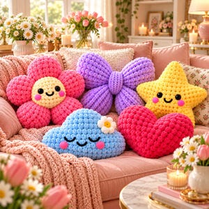 May include: A collection of five plush pillows in various shapes including a pink flower, a purple butterfly, a yellow star, a blue cloud with a small white flower, and a red heart. Each pillow features a textured, crocheted surface.
