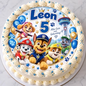 Könnte beinhalten: Ein runder Kuchen mit weißer Glasur und blauen Streuseln, verziert mit einem Paw Patrol-Aufleger, dem Namen Leon, der Zahl 5 und dem Text Alles Gute zum Geburtstag. Das Motiv zeigt die Charaktere Skye, Marshall, Chase, Rubble und Rocky.