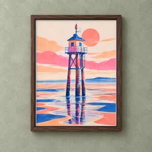 Op de afbeelding: Een ingelijste kunstdruk met een hoge vuurtoren op stelten in ondiep water bij zonsondergang. De scène toont een grote oranje zon, roze en perzikkleurige wolken en een blauwe en oranje reflectie op het natte zandoppervlak.