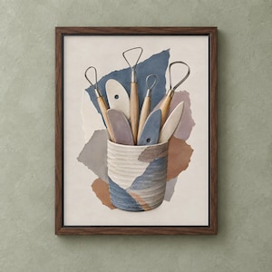 May include: A framed wall art print featuring a textured ceramic cup filled with various pottery tools, including wire loops and wooden ribs. The composition is set against a background of layered, torn paper shapes in muted blue, brown, and cream tones.