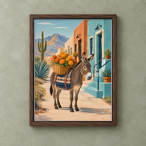 May include: A framed wall art print depicting a donkey carrying a woven basket filled with bright orange marigolds on its back. The donkey wears a patterned saddle blanket. The scene features a desert street with cacti and mountains.