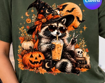May include: A dark olive green t-shirt featuring a graphic of a raccoon wearing a witch hat and sunglasses, drinking an iced beverage while making a peace sign. The design includes a large orange moon, bats, pumpkins, a skull, and books.