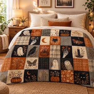 May include: A patchwork quilt featuring a grid of squares with autumn-themed illustrations including ghosts, owls, black cats, crows, pumpkins, moths, butterflies, crescent moons, skeletal hands, and candles in shades of orange, black, and grey.