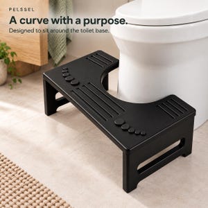 May include: A black toilet stool with a U-shaped cutout designed to fit around a toilet base. The top surface features textured grip lines and circular foot-shaped patterns. Text on the image reads: PELSSEL A curve with a purpose. Designed to sit around the toilet base.