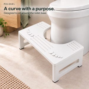 May include: A white bathroom toilet stool featuring a curved cutout designed to fit around the base of a toilet. The top surface includes raised foot-shaped traction pads and linear grooves. Text on the image reads: PEL SSEL A curve with a purpose.