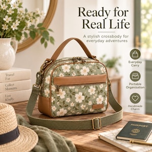 May include: A sage green crossbody bag with a white floral pattern, brown leather-like trim, a top handle, and an adjustable olive green canvas strap. The bag features a front zippered pocket and metal hardware. Text reads: Ready for Real Life.