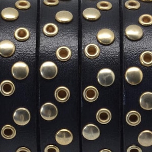 May include: Close-up of black leather straps with gold-toned metal rivets and eyelets. The straps are arranged in a row, showing the detail of the rivets and eyelets.