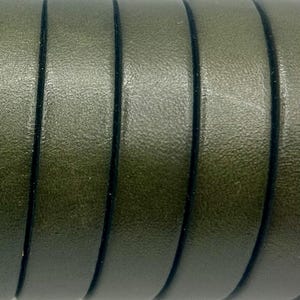 May include: Close-up of olive green leather strips with black edges. The strips are curved and have a textured surface, creating a repeating pattern. The image highlights the material's color and texture.