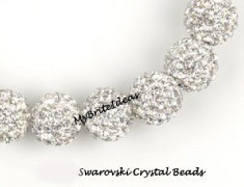 May include: Close-up of a strand of silver Swarovski crystal beads. The beads are round and covered in small, sparkling crystals. The text "MyBriteIdeas" and "Swarovski Crystal Beads" are visible.