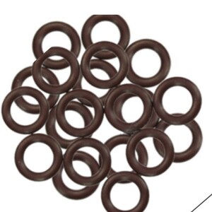 Könnte beinhalten: Ein Haufen brauner Gummidichtungen. Die Ringe sind alle gleich groß und in einem zufälligen Muster angeordnet.