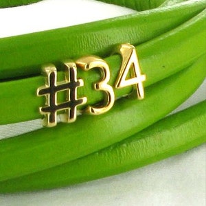 May include: A green leather bracelet with a gold charm that says "#34".