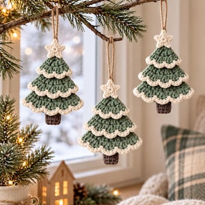 Crochet Christmas tree ornament used as a festive napkin decoration on a neutral holiday table setting with pine greenery and warm Christmas lights.

Handmade sage green crochet Christmas tree ornament hanging from a wooden door knob beside evergreen garland and pinecones in a cozy holiday entryway.

Three layered crochet Christmas tree ornaments hanging from a natural branch near a bright window with soft Scandinavian Christmas home decor.