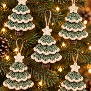 May include: Five handmade crochet Christmas tree ornaments in sage green with cream-colored scalloped edges and a cream star topper. Each tree features a brown trunk and a jute twine loop for hanging, displayed as a set of festive decorations.