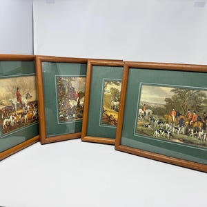 May include: Four framed prints depicting traditional fox hunting scenes with riders on horseback and packs of hounds. Each print is encased in a medium-toned wooden frame with a dark green matting, showcasing detailed outdoor landscapes.