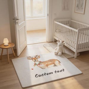 Puede incluir: Una alfombra rectangular con una ilustración en acuarela de un cervatillo que lleva una corona festiva alrededor del cuello. La alfombra tiene un fondo color crema claro e incluye el texto negro Custom text impreso bajo el ciervo.