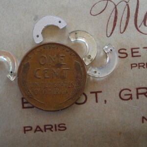 May include: A close-up of a US one-cent coin with the words "ONE CENT" and "UNITED STATES OF AMERICA" inscribed on it. The coin is surrounded by four clear plastic pieces, each shaped like a half-circle.