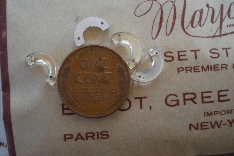 May include: A close-up of a US one-cent coin with the words "ONE CENT" and "UNITED STATES OF AMERICA" inscribed on it. The coin is surrounded by four clear plastic pieces, each shaped like a half-circle.