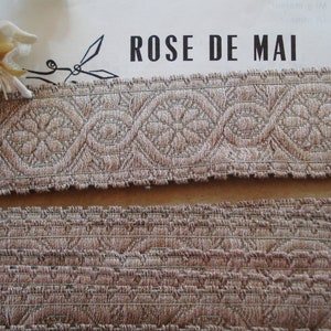 Puede incluir: Dos piezas de ribete beige con un patr&oacute;n tejido. La pieza superior tiene un dise&ntilde;o m&aacute;s intrincado con un motivo floral repetitivo. La pieza inferior tiene un dise&ntilde;o m&aacute;s simple y texturizado. El texto "ROSE DE MAI" es visible en el fondo.