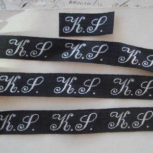 1920 Frans wit zwart fancy monogram beginletter "KP" zijdesatijn appliqué textiel kledingmaker label hoedenmakerij lintversiering