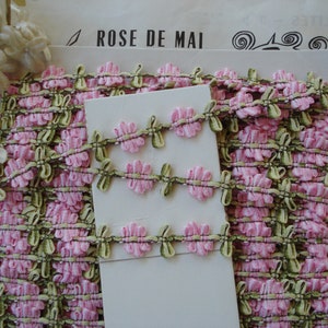 May include: Pink and green trim with a floral design. The trim is labeled "ROSE DE MAI".