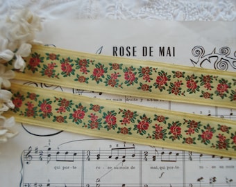 Puede incluir: Dos piezas de cinta amarilla con un patrón repetido de flores rojas y verdes. La cinta está sobre una hoja de música con las palabras "A ROSE DE MAI" impresas en ella.