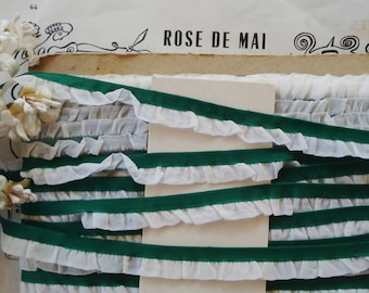 May include: A close-up of white ruffled trim with green velvet ribbon. The ribbon is layered on top of the trim, creating a striped pattern. The text "ROSE DE MAI" is visible in the background.