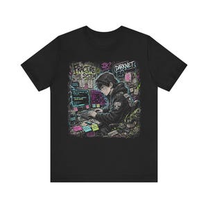 Könnte beinhalten: Ein schwarzes T-Shirt mit einem Grafikdruck einer Person mit Kapuzenpullover, die an einem Computertisch sitzt. Das Design enthält den Text "FRACTURE THE SYSTEM" und "DARKNET" sowie neonfarbene Haftnotizen, Computerbildschirme und Unordnung.